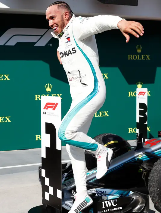 Lewis Hamilton melompat dari mobilnya merayakan kemenagan menjuarai GP Hungaria di Sirkuit Hungaroring, Mogyorod, (29/7). Kemenangan ini sekaligus menempatkan Hamilton berada di puncak klasemen. (AP Photo/Laszlo Balogh)