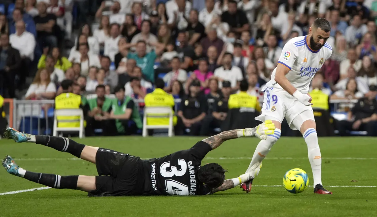 Penjaga gawang Levante Dani Cardenas (kiri) melakukan penyelamatan di depan pemain Real Madrid Karim Benzema pada pertandingan sepak bola La Liga Spanyol di Stadion Santiago Bernabeu, Madrid, 12 Mei 2022. Real Madrid menang 6-0. (AP Photo/Manu Fernandez)