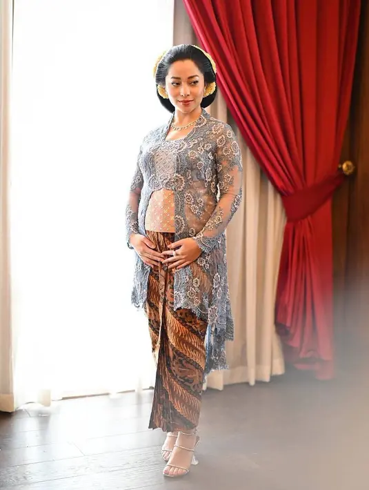 Di sini, Nikita Willy mengenakan kebaya dengan baby bump yang terlihat. Ia mengenakan kebaya biru dengan bordir floral yang sangat cantik, dipadukan mengenakan kain batik cokelat yang serasi. [Foto: Instagram/svarna_byikatindonesia]