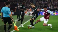 Gelandang West Ham United asal Meksiko #19, Edson Alvarez (Kanan), melompat untuk menjegal gelandang Arsenal asal Norwegia #08, Martin Odegaard (Tengah), selama pertandingan Liga Primer Inggris antara West Ham United dan Arsenal di Stadion London, London, Minggu dini hari WIB (1/12/2024). (HENRY NICHOLLS/AFP)