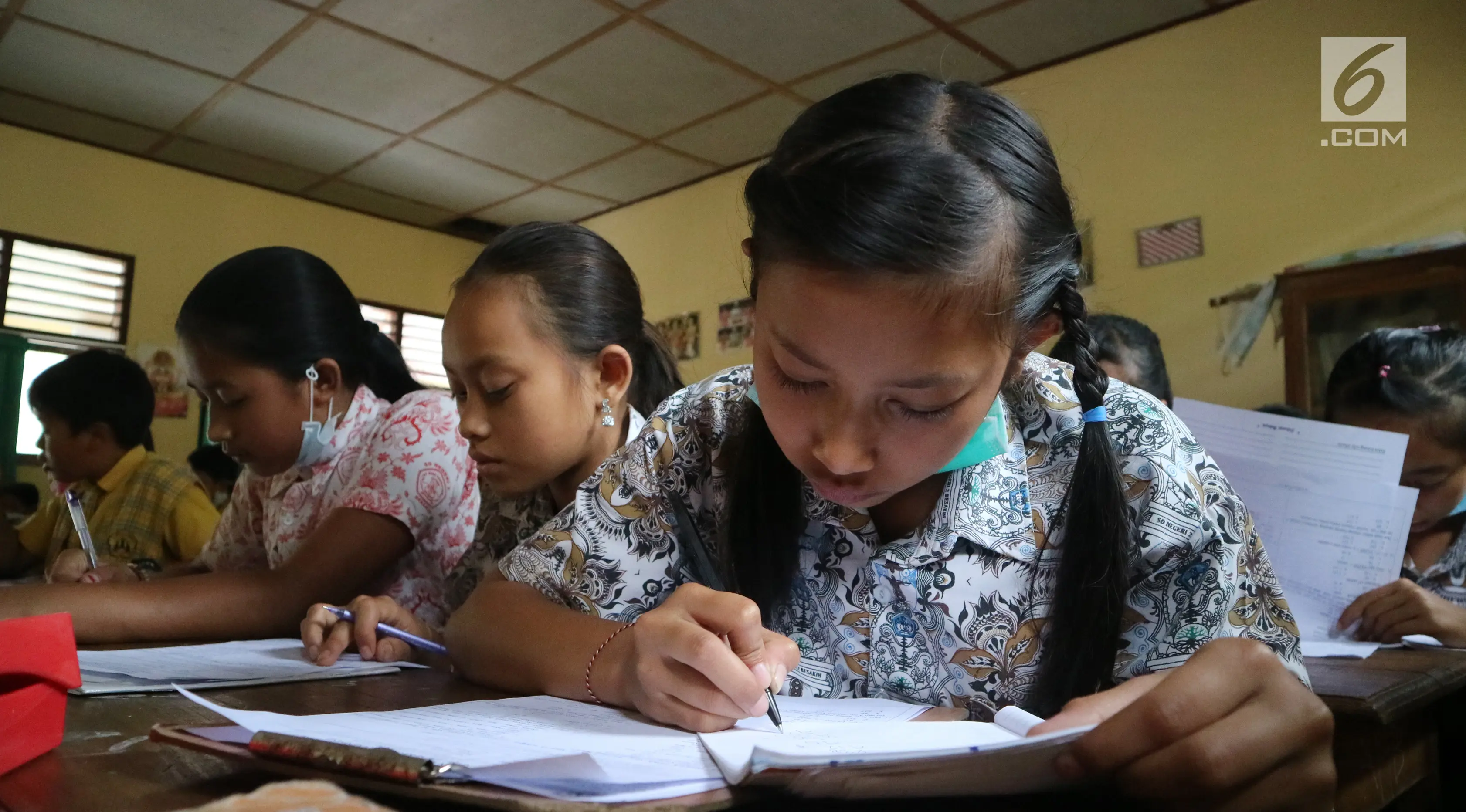 Para siswa mengejrjakan soal UAS di SD Negeri 4 Rendang, Karangasem, Bali, Rabu (29/11). Meskipun status Gunung Agung sudah menjadi awas, para siswa tetap masuk sekolah dengan mengenakan masker. (Liputan6.com/Andi Jatmiko)