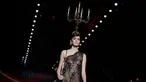 Model mengenakan busana rancangan Moschino dengan hiasan kepala berbentuk tempat lilin dalam Milan Fashion Week Autumn/Winter 2017 di Milan, Italia, (23/2). (AFP Photo / Marco Bertorello)