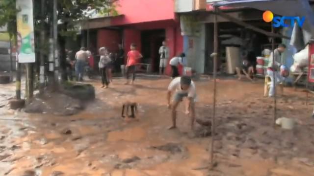 Sebuah alat berat dikerahkan untuk membantu petugas kebersihan dan warga menyingkirkan lumpur hingga arus lalu lintas tersendat.