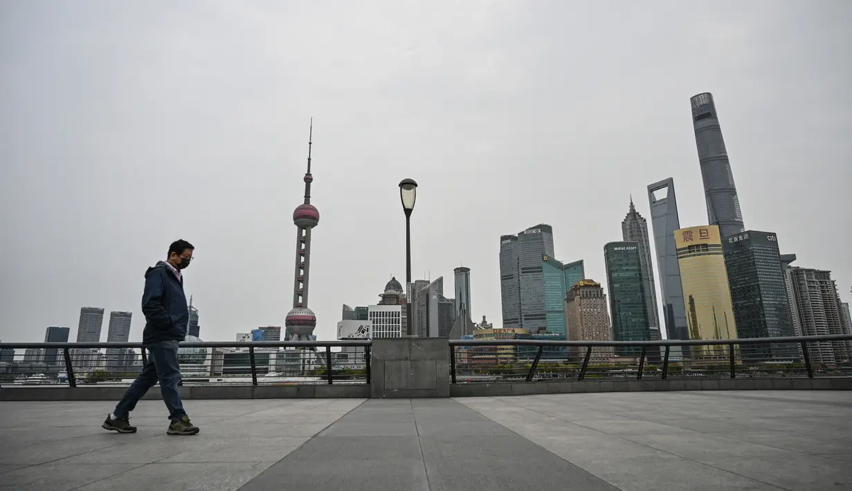 Seorang pria berjalan di sepanjang Sungai Huangpu di distrik Pudong yang dikunci sebagai tindakan melawan Covid-19, di Shanghai (28/3/2022).  Shanghai  lockdown setiap setengah kota secara bergiliran untuk tes Covid-19 massal mulai Senin (28/3/2022) di tengah lonjakan infeksi. (AFP/Hector Retamal)