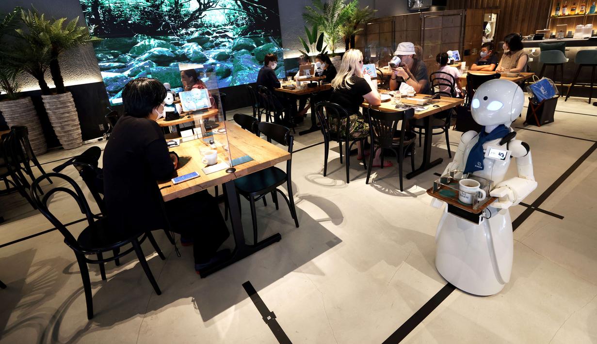 Robot humanoid mengantarkan minuman kepada pelanggan di Dawn Cafe, Tokyo, Jepang, 17 Agustus 2021. Peluncuran kafe ini bersamaan dengan Paralimpiade yang akan dibuka pada 24 Agustus. (Behrouz MEHRI/AFP)