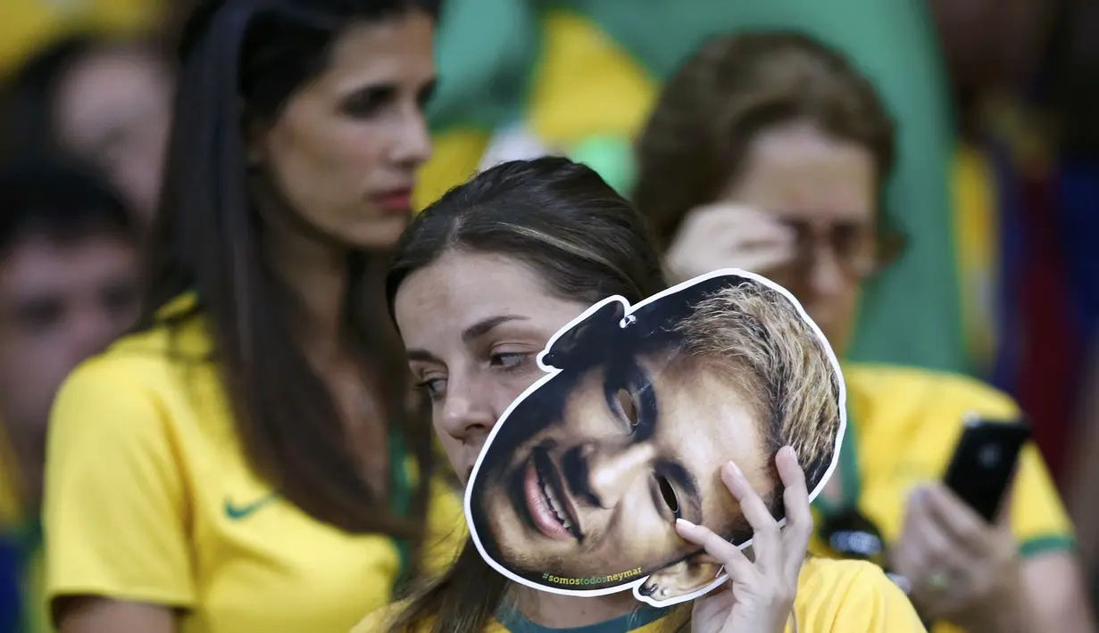 Seorang fans perempuan yang memegang topeng wajah Neymar tak bisa menahan kekecewaannya setelah Brasil dibantai Jerman dengan skor 1-7, Selasa (8/7/14). (REUTERS/Marcos Brindicci)