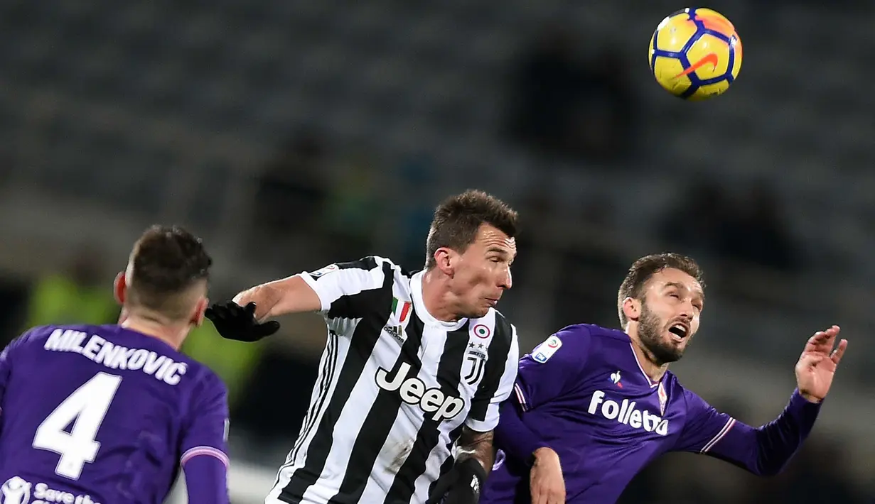 Penyerang Juventus, Mario Mandzukic (tengah) berebut bola udara dengan bek Fiorentina, German Pezzella (kanan) saat bertanding pada lanjutan Liga Serie A Italia di stadion Atemio Franchi, Florence (9/2). Juventus menang 2-0. (AFP Photo/Filippo Monteforte)