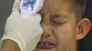 Seorang anak laki-laki mendapatkan pemeriksaan suhu badan oleh petugas tiba di Bandara Internasional Bangkok Suvarnabhumi, Thailand, Minggu (21/6/2015). WHO mencatat ada 1.334 kasus MERS di 26 negara. (REUTERS/Kerek Wongsa)