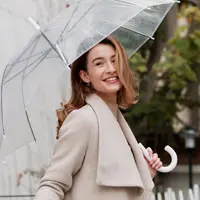 Wanita yang berpose tersenyum sambil memegang payung (Foto: Freepik/freepik).