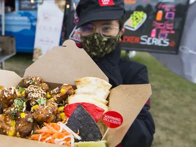 Penjual yang mengenakan masker memperlihatkan hidangan ayam goreng saat Festival Ayam Goreng di Toronto, Kanada, 20 September 2020. Festival yang digelar di tengah pandemi COVID-19 tersebut berlangsung pada 19-20 September 2020 dengan menghadirkan sekitar 30 jenis ayam goreng. (Xinhua/Zou Zheng)