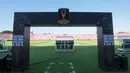 Gapura resmi Piala Presiden 2026 berdiri di tepi lapangan Stadion Kapten I Wayan Dipta, Gianyar, Bali, sebagai simbol kesiapan venue menyambut partai final yang mempertemukan Persib Bandung dan Persebaya Surabaya. Laga ini kembali memperpanjang rivalitas klasik dua klub besar Indonesia yang telah puluhan kali berhadapan di kompetisi nasional. Persib melaju ke final usai mengalahkan Persija Jakarta 2-1, sementara Persebaya memastikan tiket setelah menyingkirkan Arema FC di babak semifinal. (KapanLagi.com/Budy Santoso)