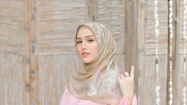 Padukan gamis berwarna pink pastel dengan hijab bermotif  berwarna coklat pastel seperti Adelia Pasha ini. [Instagram/adeliapasha]