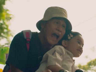 Vino G. Bastian yang berperan sebagai Dodo Rozak bersama putrinya, Kartika (Graciella Abigail) tengah menikmati alam bebas bersama balon warna-warni. (Foto: YouTube)