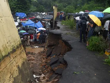 Petugas penyelamat dan warga berkumpul di lokasi runtuhnya tembok di Mumbai, India (2/7/2019). Sedikitnya 15 orang tewas dan 69 orang lainya luka ketika sebuah tembok runtuh saat hujan lebat monsun. (AFP Photo/Punit Paranjpe)