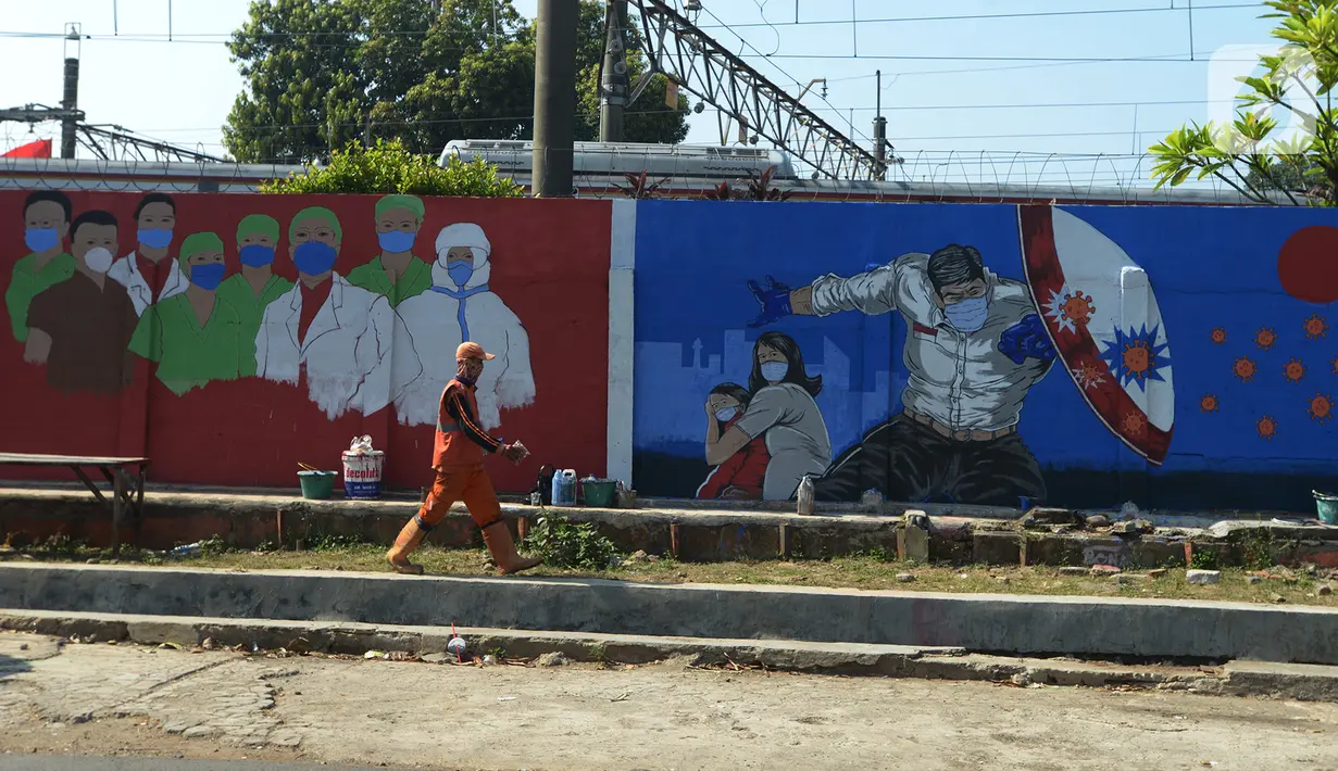 Petugas PSSU Kelurahan Bukit Duri melintasi mural bertemakan COVID-19 di kawasan Manggarai, Bukit Duri, Jakarta, Jumat (28/8/2020). Mural tersebut dibuat untuk meningkatkan kepatuhan masyarakat akan protokol kesehatan karena kasus COVID-19 nasional terus meningkat. (merdeka.com/Imam Buhori)