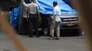 Petugas melihat melihat kondisi mobil yang dirusak di Polsek Ciracas, Jakarta, Rabu (12/12). Mobil yang dirusak massa tak dikenal saat ini ditutup dengan menggunakan terpal biru. (Liputan6.com/Herman Zakharia)