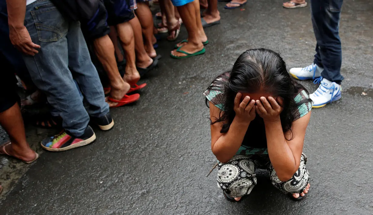 Salah satu anggota keluarga menangis saat melihat tubuh Nora Acielo tewas ditembak orang tak dikenal di Manila, Filipina, Kamis (8/12). Acielo ditembak saat sedang mengantarkan kedua anaknya berangkat sekolah. (REUTERS/Erik De Castro)