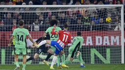 Bek Girona, Valery Fernandez (tengah) melepaskan tendangan yang menghasilkan gol pertama timnya ke gawang Atletico Madrid pada laga pekan ke-19 Liga Spanyol 2023/2024 di Montilivi Stadium, Girona, Kamis (4/1/2024) dini hari WIB. (AFP/Pau Barrena)