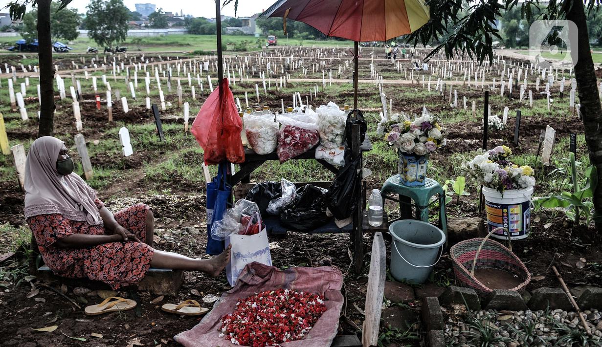 Pedagang bunga tertidur di dekat komplek makam protokol Covid-19 di TPU Bambu Apus, Jakarta, Selasa (2/3/2021). TPU Bambu Apus kini tidak lagi menampung pemakaman jenazah protokol Covid-19 akibat lahan di dua blok sudah penuh dan dialihkan ke TPU Srengseng Sawah. (merdeka.com/Iqbal S Nugroho)