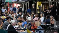 Pelanggan menikmati makan siang di meja di luar restoran di Soho, London, ketika pemerintah Inggris mempertimbangkan pembatasan baru pada Minggu (20/9/2020). Inggris kemungkinan akan kembali memberlakukan tindakan lockdown akibat lonjakan tajam infeksi virus corona COVID-19. (DANIEL LEAL-OLIVAS/AFP)