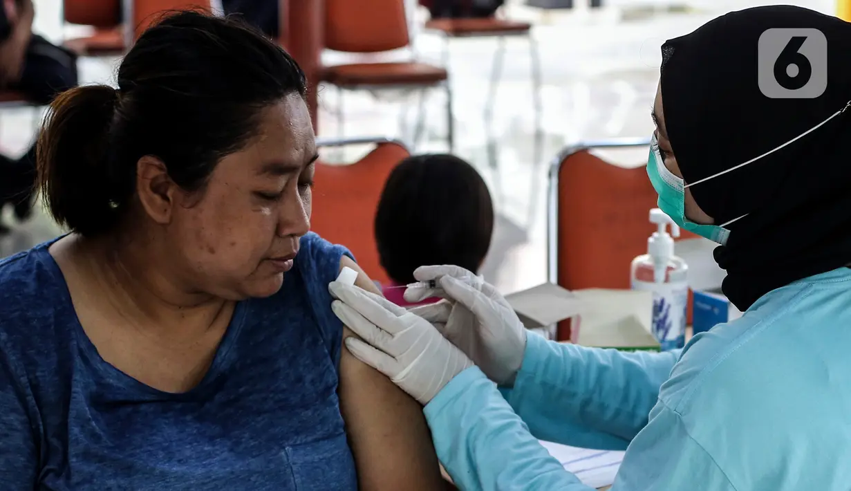 Petugas menyuntikkan vaksin COVID-19 dosis ketiga (booster) pada seorang perempuan di RPTRA Rusun Benhil, Jakarta, Rabu (6/7/2022). Selain itu, vaksin booster juga jadi syarat bagi masyarakat yang ingin melakukan perjalanan menggunakan transportasi umum. (Liputan6.com/Johan Tallo)
