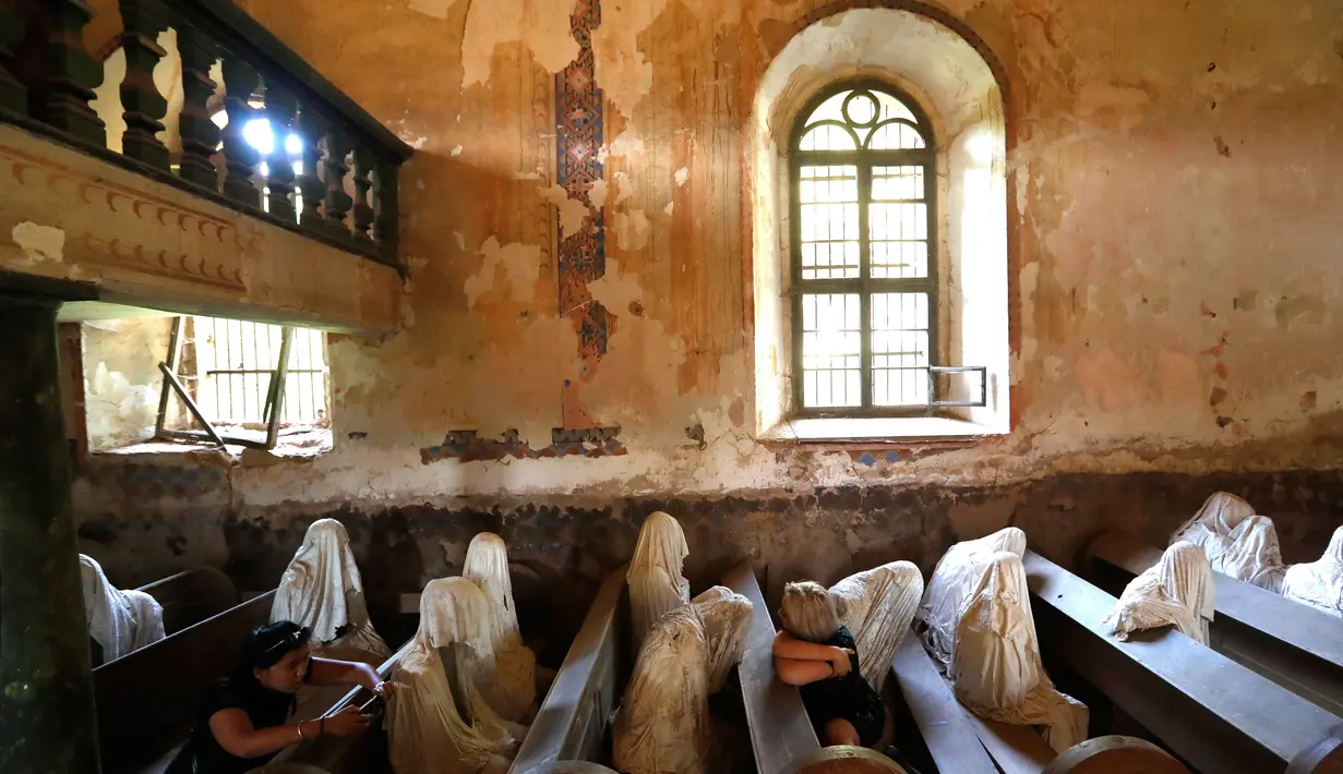 Gambar pada 30 Agustus 2018, turis Prancis mengunjungi Gereja St George yang menampilkan patung-patung serupa hantu di Lukova, Ceko. Dengan interior gereja yang sudah lapuk, tempat ini sukses menarik perhatian wisatawan dunia. (AP/Petr David Josek)