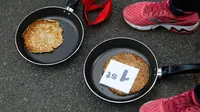 Kaia Larkas usai memenangkan lomba lari sembari membawa wajan berisi pancake di Kota Olney, Buckinghamshire, Inggris, Selasa (28/2). Lomba yang digelar pada Hari Pancake atau Pancake Day ini diadakan satu hari menjelang Rabu Abu. (AP Photo/Alastair Grant)