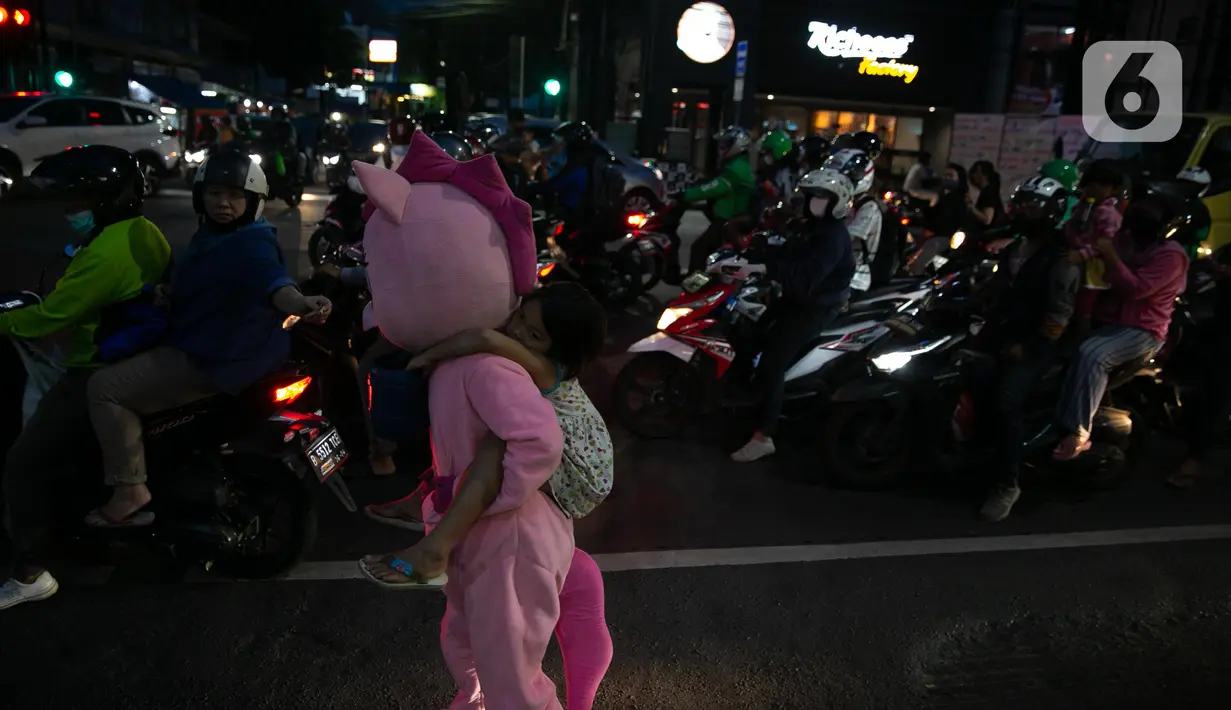 Warkuatno (41) bersama anak sulungnya, Bunga (9) berjalan kaki di pinggir Jalan Raya Fatmawati, Jakarta, Rabu (6/1/2021). Mantan sopir Metromini 75 ini menjadi badut keliling sejak bulan Maret lalu, tak lama setelah kasus corona COVID-19 terdeteksi di Indonesia. (Liputan6.com/Faizal Fanani)