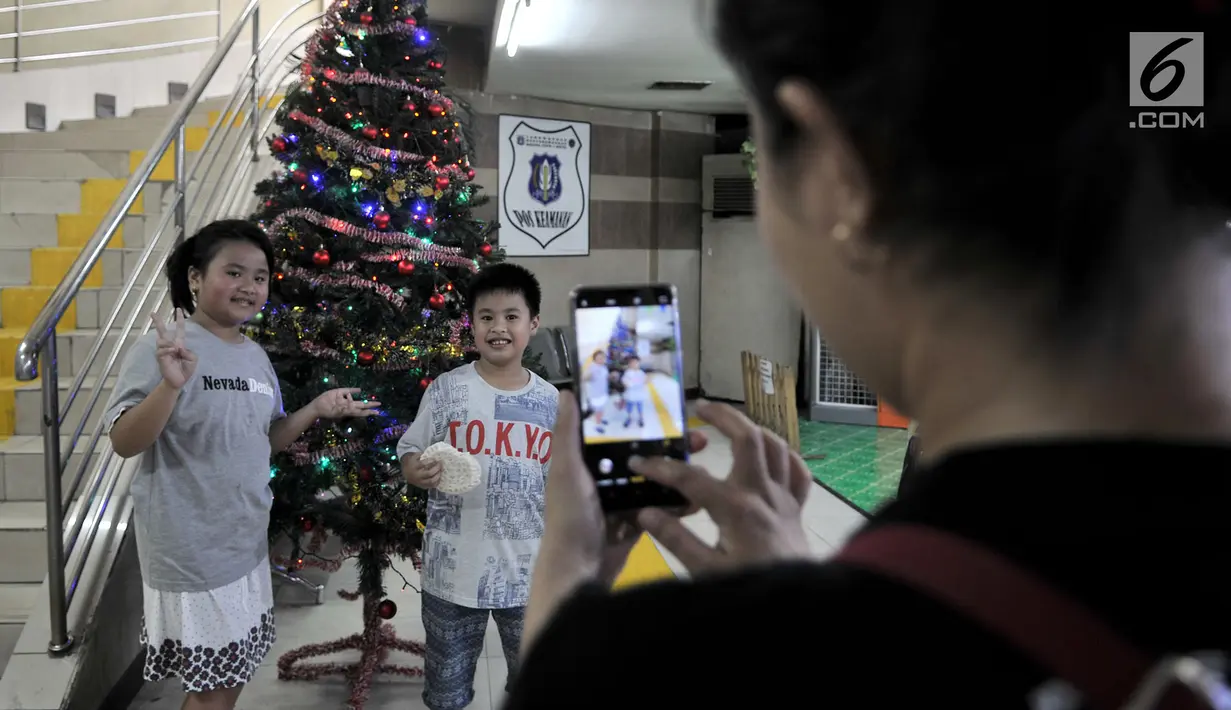 Pejalan kaki berfoto dengan pohon Natal yang menghiasi tempat penyeberangan orang (TPO) Kota Tua, Jakarta, Kamis (20/12). TPO yang menghubungkan Stasiun Kota Tua dan Halte Transjakarta itu berhias ornamen Natal dan Tahun Baru. (Merdeka.com/Iqbal Nugroho)