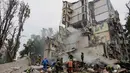 Tim penyelamat membersihkan puing-puing saat bekerja di lokasi bangunan tempat tinggal yang hancur akibat serangan udara Rusia di Kyiv pada 31 Juli 2025. (Tetiana DZHAFAROVA/AFP)