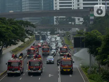 Petugas pemadam kebakaran (Damkar) dengan mobil pemadam melakukan penyemprotan cairan disinfektan di sepanjang jalan Thamrin-Sudirman, Jakarta, Sabtu (28/3/2020). Penyemprotan dilakukan untuk meminimalisir penyebaran COVID-19 di ruang udara dan ruas jalan. (merdeka.com/Imam Buhori)