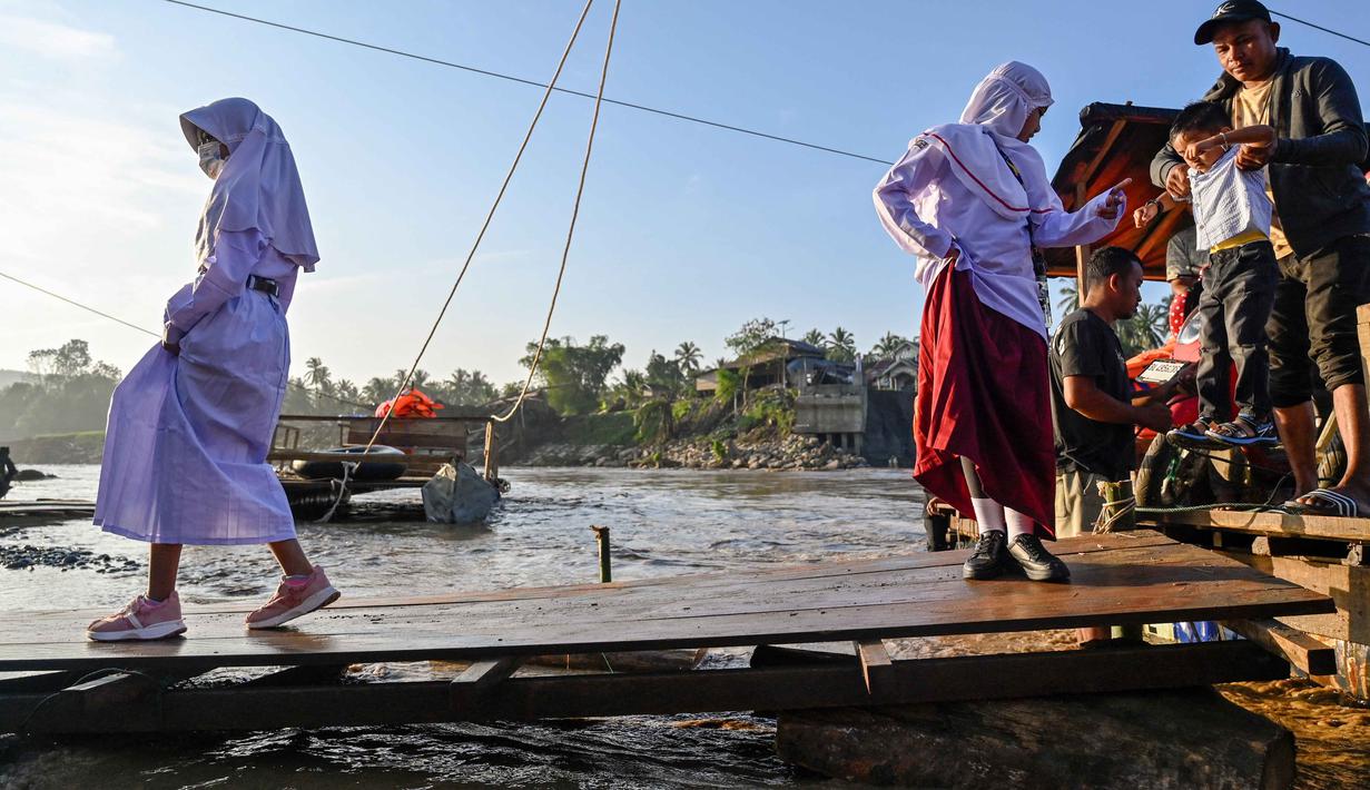 Dalam surat edaran tersebut dijelaskan, hari pertama masuk sekolah ditetapkan pada Senin, 5 Januari 2026. Tampak dalam foto, sejumlah siswa menaiki perahu darurat untuk menyeberangi Sungai Peusangan pasca banjir bandang yang menghancurkan desa-desa di sekitarnya di kabupaten Bireuen, provinsi Aceh, Indonesia pada Senin 5 Januari 2026. (CHAIDEER MAHYUDDIN/AFP)