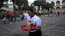 Seorang pramusaji mengacungkan jempol saat mengikuti Waiters Race ke-16 di Antigua, barat daya Ibu Kota Guatemala City, Rabu (14/11). Peserta diminta unjuk kebolehan menggunakan satu tangan membawa nampan berisi minuman. (JOHAN ORDONEZ/AFP)