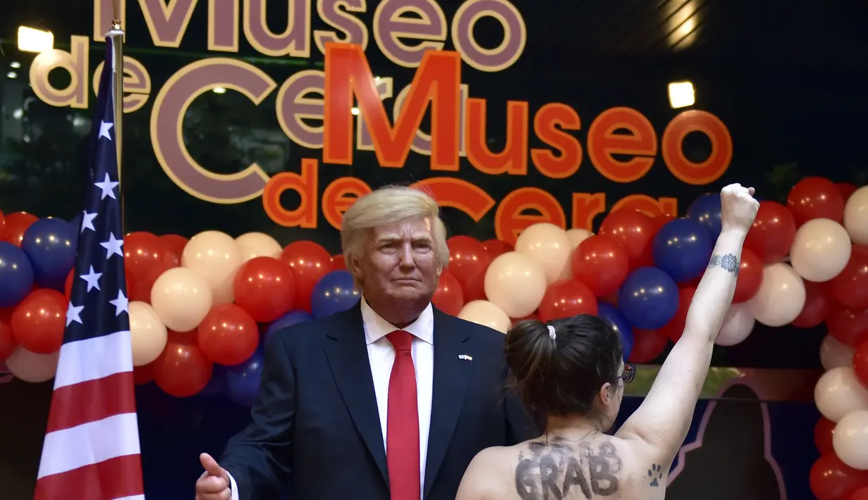 Aktivis Femen bertelanjang dada di depan patung lilin Presiden AS terpilih Donald Trump saat acara pembukaan Madrid's wax museum di Madrid, Spanyol, Selasa (17/1). (AFP PHOTO/GERARD JULIEN)