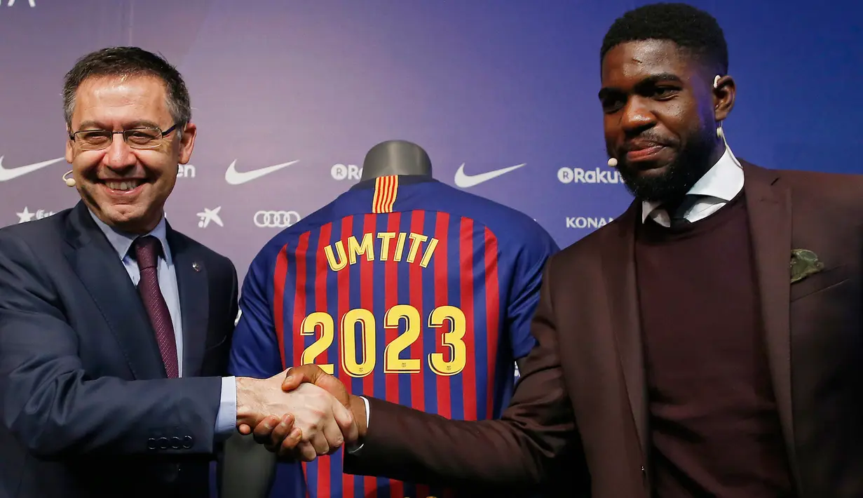 Bek asal Prancis, Samuel Umtiti dan Presiden Barcelona Josep Maria Bartomeu bersalaman pada pengumuman perpanjangan kontraknya di stadion Camp Nou, Senin (4/6). Umtiti secara resmi memperpanjang kontrak dengan Barcelona hingga 2023. (AP/Manu Fernandez)