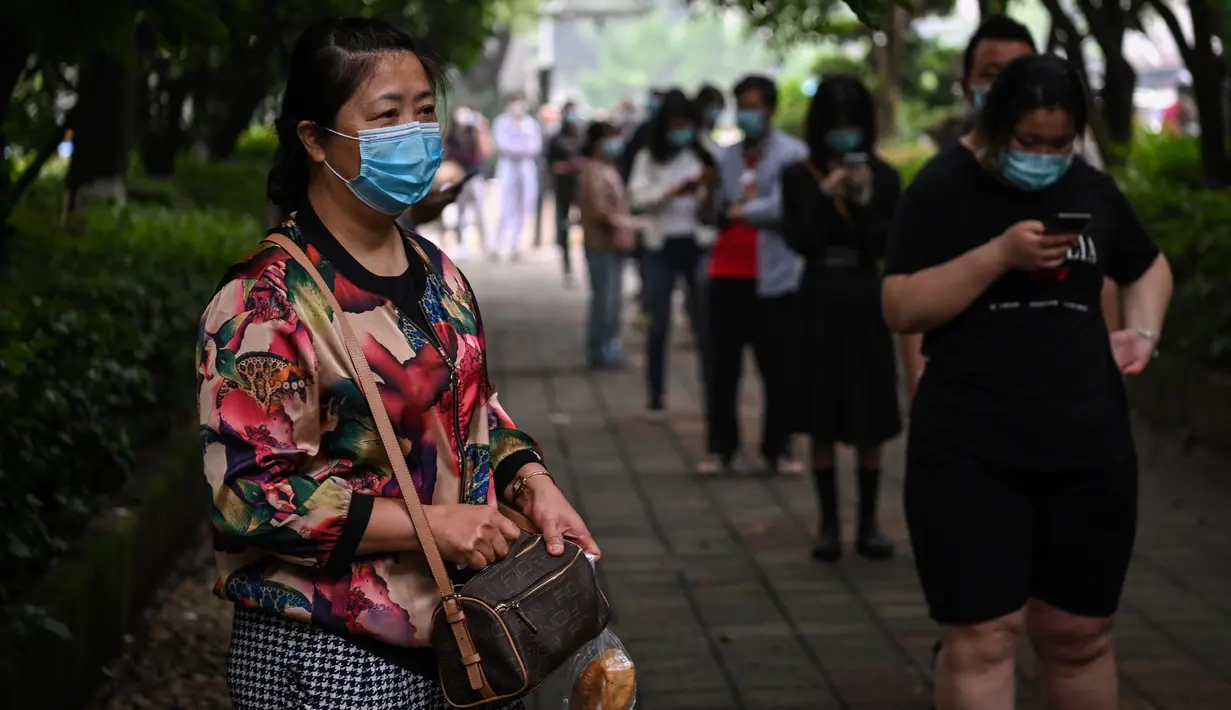 Warga mengenakan masker menunggu dalam barisan untuk tes virus corona di lingkungan di Wuhan, provinsi Hubei, Jumat (15/5/2020). Tes massal yang ditargetkan dalam 10 hari ini akibat adanya pasien Virus Corona baru di Wuhan, setelah sebulan lebih tidak ada laporan kasus baru. (Hector RETAMAL/AFP)