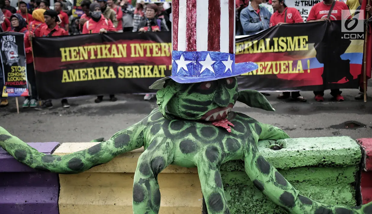 Gerakan Buruh untuk Rakyat (Gebrak) berunjuk rasa di depan Kedubes Amerika Serikat, Jakarta, Selasa (12/2). Massa pendemo membawa serta boneka gurita raksasa warna hijau yang dikenakan topi bermotif bendera Amerika Serikat. (Liputan6.com/Faizal Fanani)