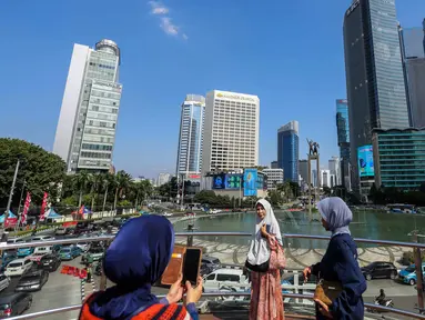 Sejumlah orang berswafoto di anjungan Transjakarta kawasan Bundaran HI, Jakarta, Selasa (1/8/2023). Menurut Badan Meteorologi, Klimatologi, dan Geofisika (BMKG) suhu udara akan berkisar 22 hingga 34 derajat Celcius di siang hari, dengan kelembaban 50-80 persen. (Liputan6.com/Faizal Fanani)