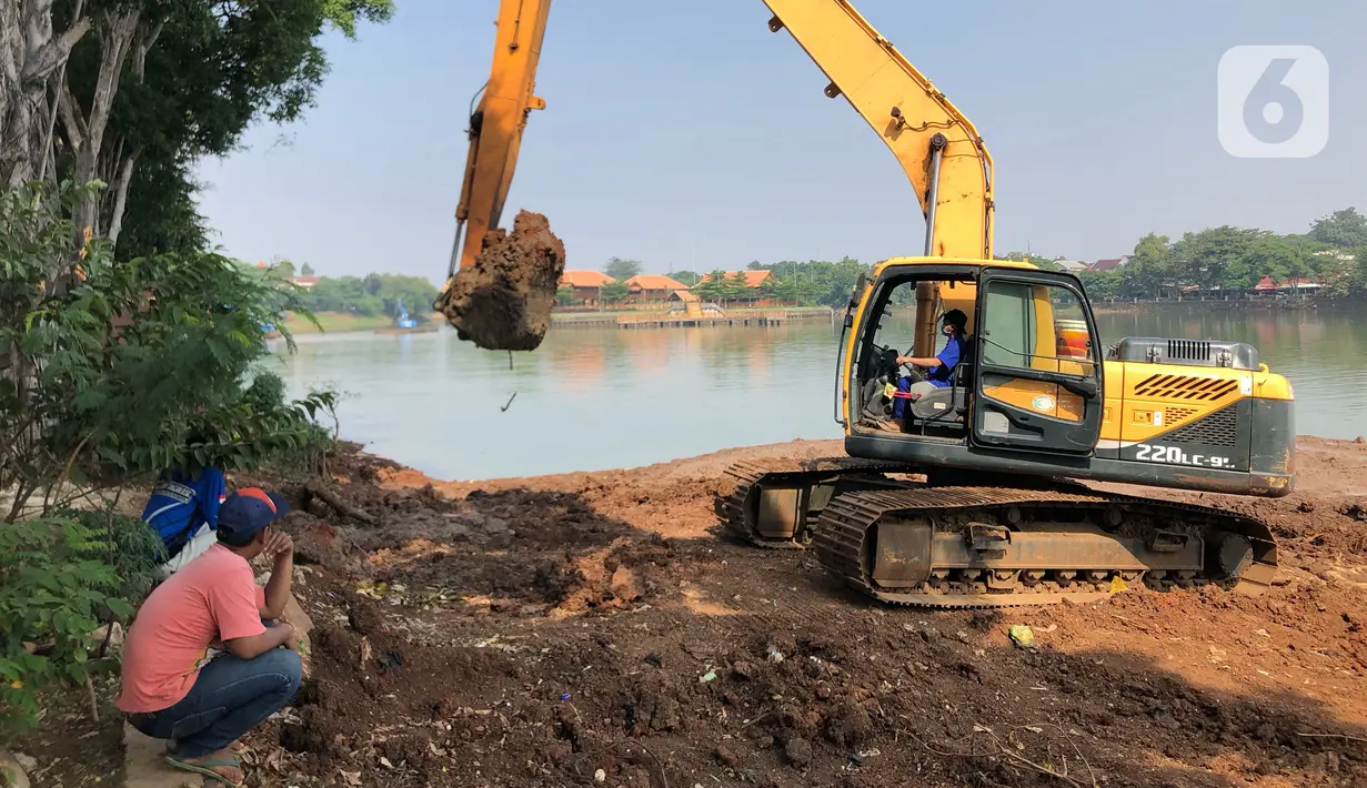 Petugas menggunakan alat berat untuk mengeruk lumpur di Setu Babakan, Jakarta, Selasa (30/6/2020). Pengerukan dilakukan guna mengembalikan kedalaman setu sehingga menambah daya tampungnya. (Liputan6.com/Immanuel Antonius)