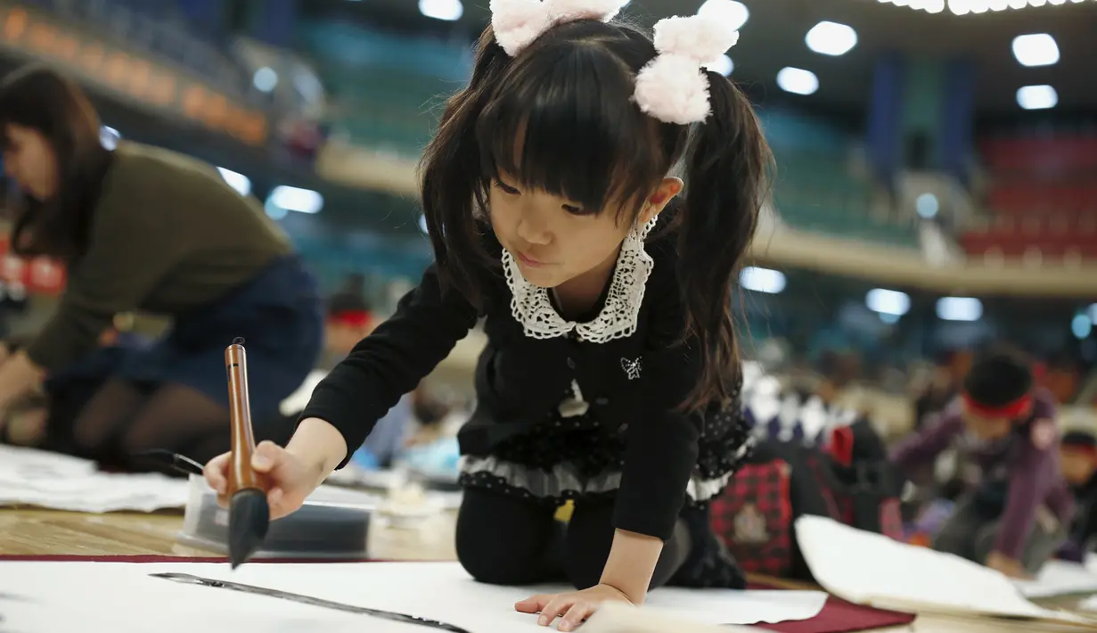 Seorang gadis kecil ikut ambil bagian kontes kaligrafi dalam merayakan tahun baru di Tokyo, Jepang, Selasa (5/1/2016). Lebih dari 3000 peserta menuliskan resolusi tahun baru di atas sebuah kanvas. (REUTERS / Thomas Peter)