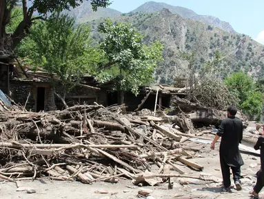 Warga mengamati bangunan rumah yang rusak akibat dihantam banjir bandang di Ursoon, daerah terpencil Chitral di Pakistan utara, Minggu (3/7). Banjir bandang akibat hujan lebat yang lama itu telah menewaskan sedikitnya 43 orang. (GUL HAMAAD Farooqi/AFP)