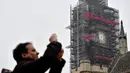 Seorang pria mengambil gambar dengan latar belakang jam Big Ben yang tidak ada jarumnya karena sedang dilakukan perbaikan dan pembersihan di London, Inggris (12/4). (AFP Photo/Ben Stansall)