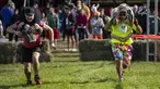 Dua tim bersaing sambil menggendong istri mereka dalam North American Wife Carrying Championship di Sunday River Resort di Newry, Maine, pada 8 Oktober 2022. Secara aturan, satu tim harus terdiri dari pria dan wanita yang telah berumur 21 tahun ke atas. (Joseph Prezioso / AFP)