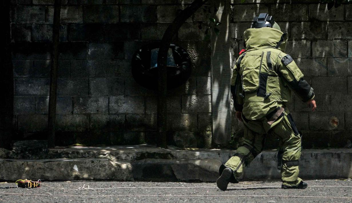 Tim dari unit penjinak bom (Jibom) satuan Brimob Polda Jabar langsung mendatangi lokasi kejadian untuk melakukan pengamanan awal. Tampak dalam foto, seorang petugas polisi dari unit penjinak bom memeriksa sebuah benda mencurigakan berbentuk kotak yang dibungkus lakban hitam dengan kabel di depan Gereja Kristen Protestan Simalungun (GKPS) di Bandung, Jawa Barat pada Jumat 19 Desember 2025. (Timur Matahari/AFP)