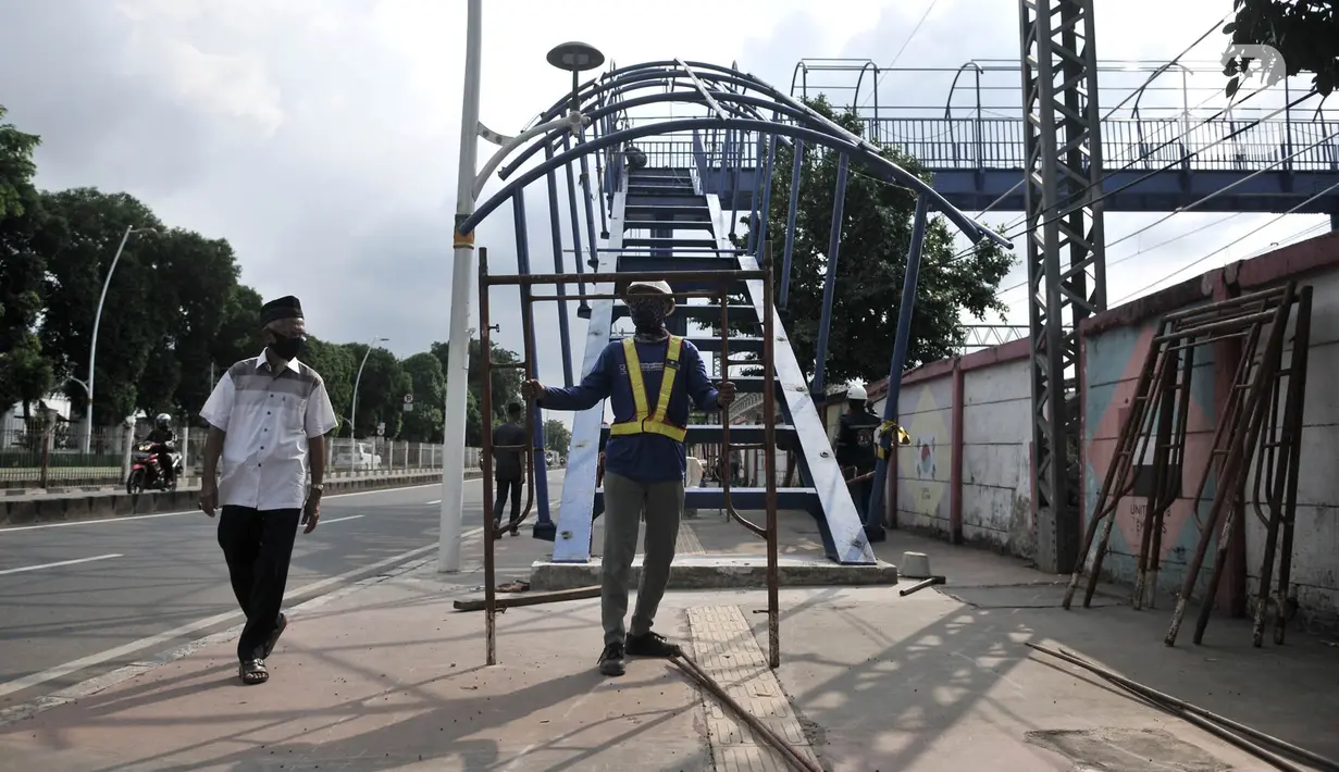 Pekerja menyelesaikan pembangunan jembatan penyeberangan orang (JPO) di dekat Stasiun Jatinegara, Jakarta, Senin (11/5/2020). JPO yang ditargetkan rampung pada tahun ini tersebut sekaligus menjadi jalur keluar penumpang kereta Stasiun Jatinegara. (merdeka.com/Iqbal S. Nugroho)