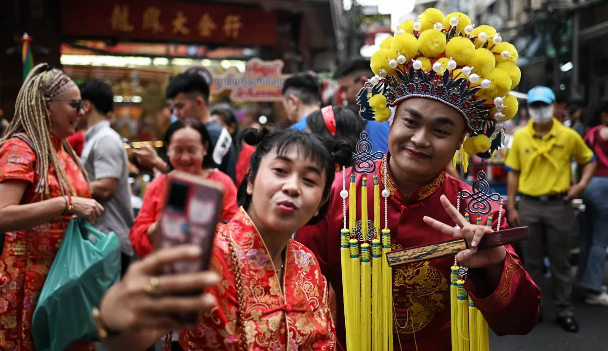 Orang-orang berfoto di sepanjang Jalan Yaowarat di Chinatown di Bangkok, 10 Februari 2024, pada hari pertama Tahun Baru Imlek Naga. (Lillian SUWANRUMPHA/AFP)