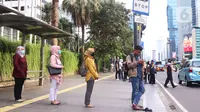 Sejumlah masyarakat melakukan jaga jarak aman di area publik di kawasan Thamrin, Jakarta, Rabu (18/3-2020). Jaga jarak atau prosedur social distancing measure harus diterapkan kepada masyarakat yang masih melakukan aktivitas di luar untuk memghindari penyebaran Covid-19. (Liputan6.com/Angga Yuniar)