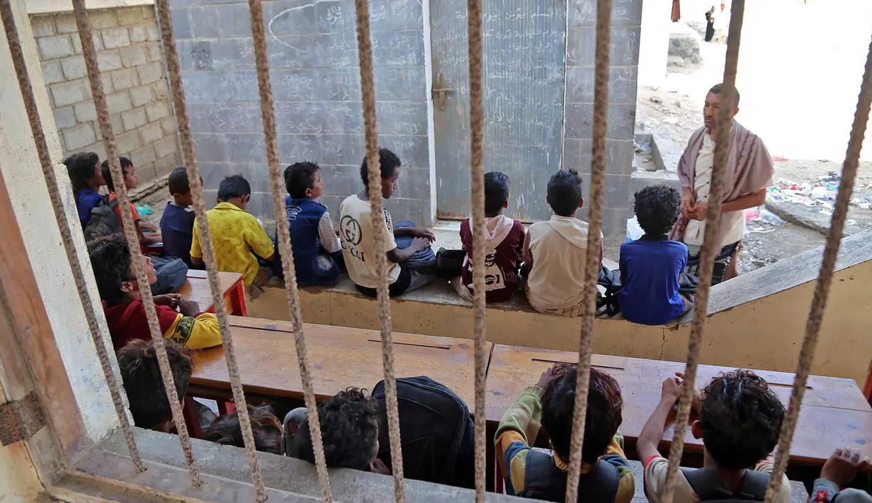Anak-anak Yaman menghadiri kelas di luar ruangan sebuah sekolah yang rusak parah pada hari pertama tahun ajaran baru di provinsi barat Yaman yang dilanda perang Hodeida, Senin (17/10/2022). UNICEF memperkirakan bahwa lebih dari dua juta anak telah putus sekolah di Yaman, peningkatan hampir setengah juta sejak perang pecah pada 2015. (Foto oleh Khaled ZIAD / AFP).