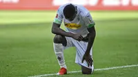 Pemain Borussia Moenchengladbach, Marcus Thuram, melakukan selebrasi berlutut untuk menghormati mendiang George Floyd pada laga Bundesliga di Stadion Borussia-Park, Minggu (31/5/2020). Moenchengladbach menang 4-1 atas Union Berlin. (AP/Martin Meissner)