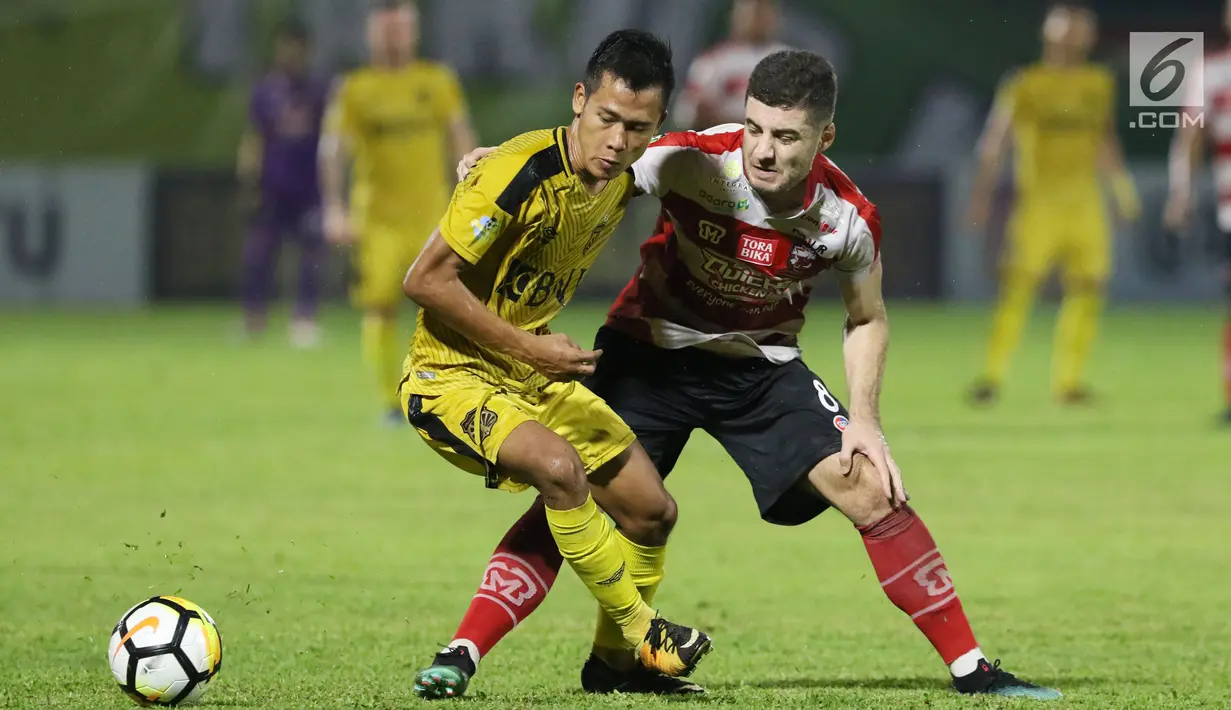 Pemain depan Bhayangkara FC, Wahyu Subo Seto (kiri) berebut bola dengan gelandang Madura United, Nuriddin Davronov pada lanjutan Go-Jek Liga 1 Indonesia 2018 bersama Bukalapak di Stadion PTIK, Jakarta, Kamis (7/6). (Liputan6.com/Helmi Fithriansyah)